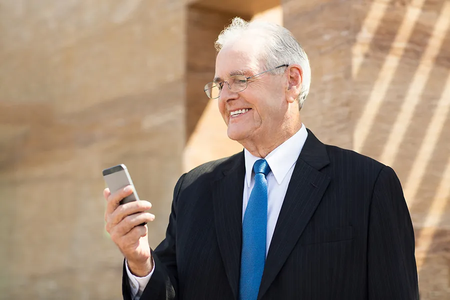 Senior business man watching the phone and smiling - Freepik